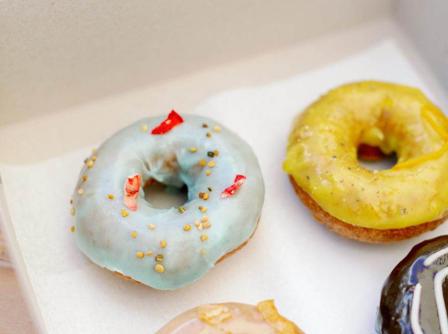 In the image, we can see a white box with four donuts of different toppings.