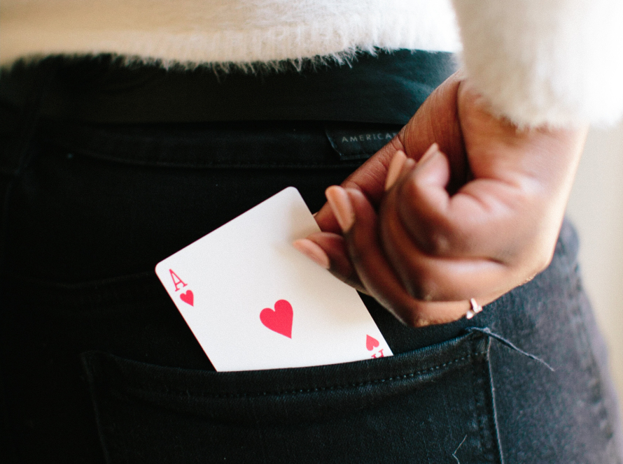In the image, a woman can be seen taking out of the back pocket of her jeans an ace in the hand.