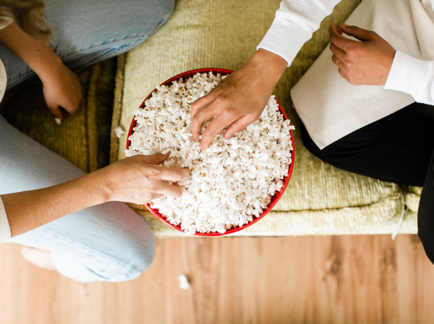 In the image you can see two people sitting on the floor eating popcorn