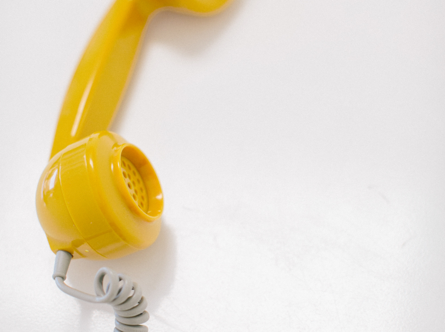 In the image, we can see an old telephone tube, yellow in color and with white cable.
