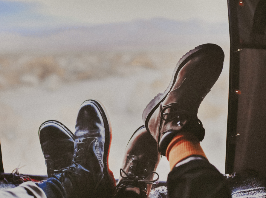 In the image we can see the feet of two tourists facing the window of a tent, whose background is a diffuse landscape