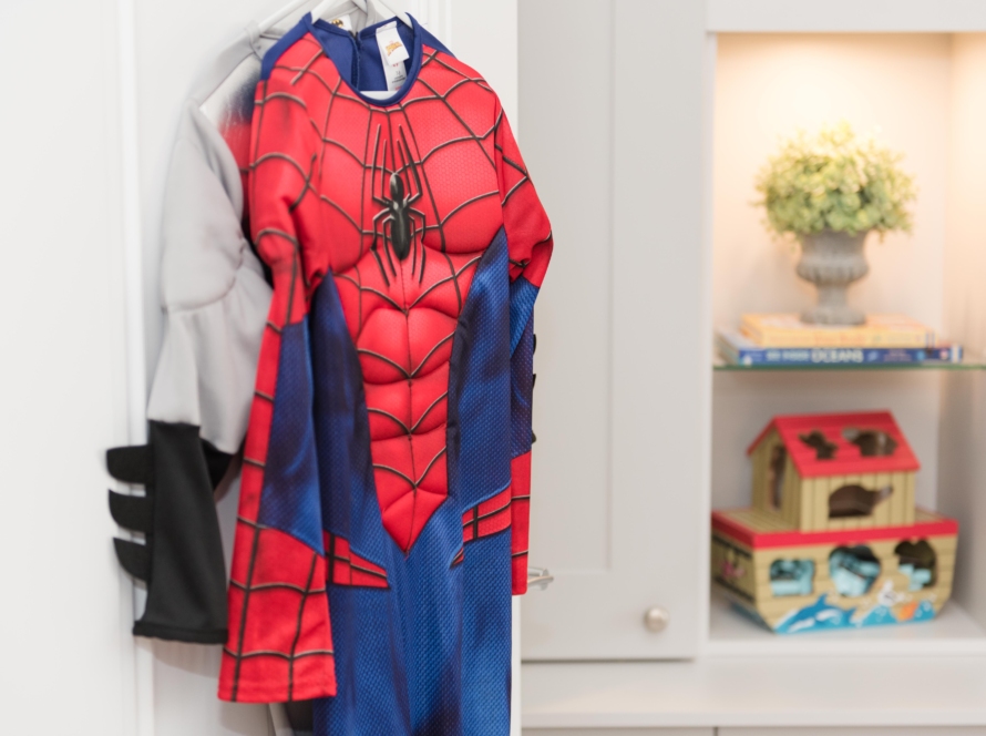 In the image we can see costumes, one of them Spider-Man, hanging on the wall of a room apparently belonging to a girl.