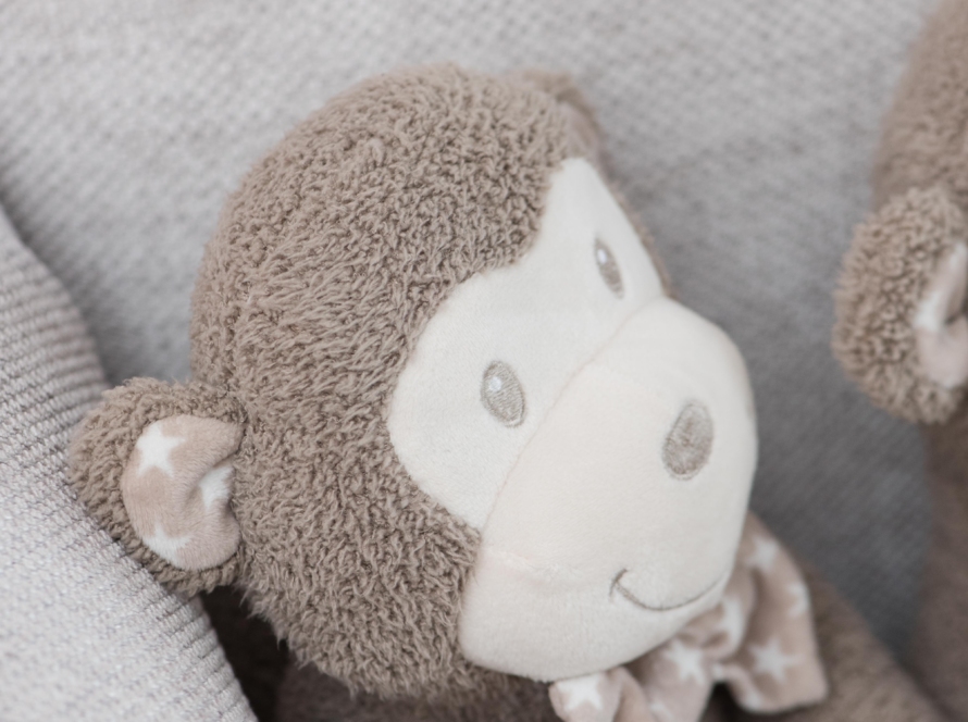 In the image we can see a stuffed monkey, in gray and white tones, sitting in an armchair in composition
