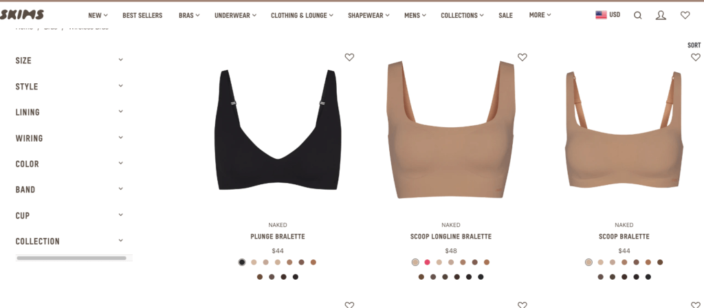 The SKIMS website, showcasing 3 bras. One black plunge bralette, one scoop longline bralette, and one scoop bralet -- all shown in naked. You're able to choose the color of the naked that matches your skintone with dots at the bottom of each bralette, showcasing the colors.
