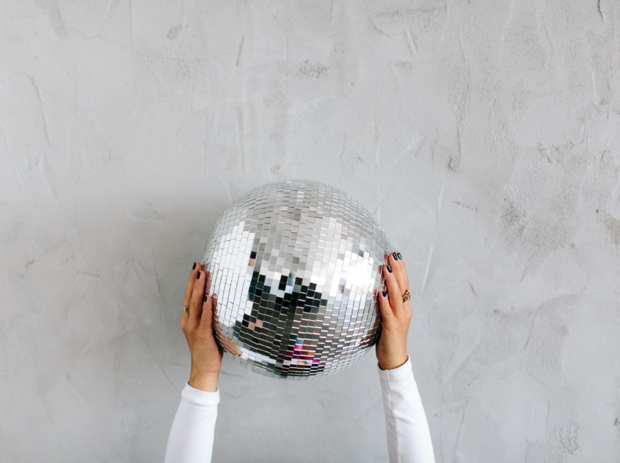 In the image we can see two women's hands holding a shiny disco sphere