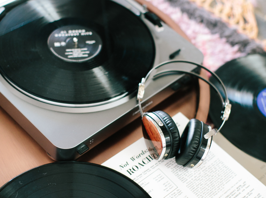 In the image, we can see a portable LP player, headphones, LPs, and a notebook.