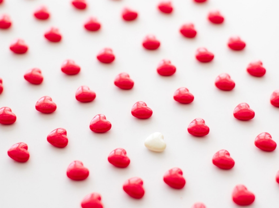 In the image, we can see very ordered rows of red hearts, and a white one standing out among them.