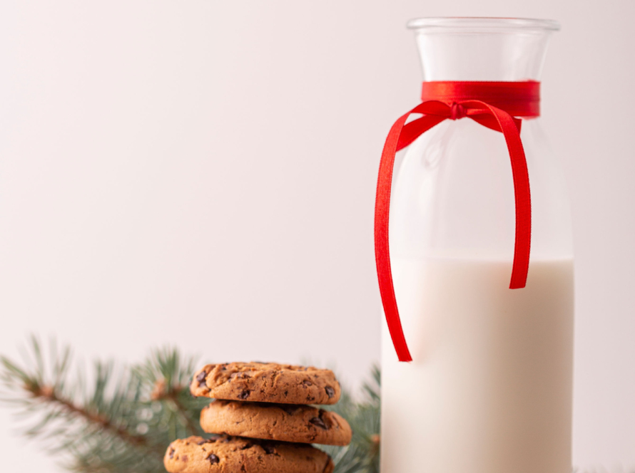 In the image, we can see a bottle of milk, and some stacked cookies, all on a round wooden board.