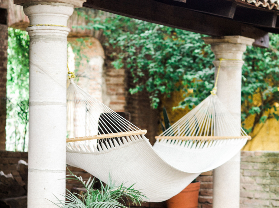 In the image we can see a gallery with Roman-style columns, some vegetation and a hammock to lie down, giving a feeling of calm and relaxation.