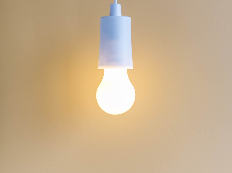 In the image we can see a lamp holder with a white LED light lamp, with a beige background.